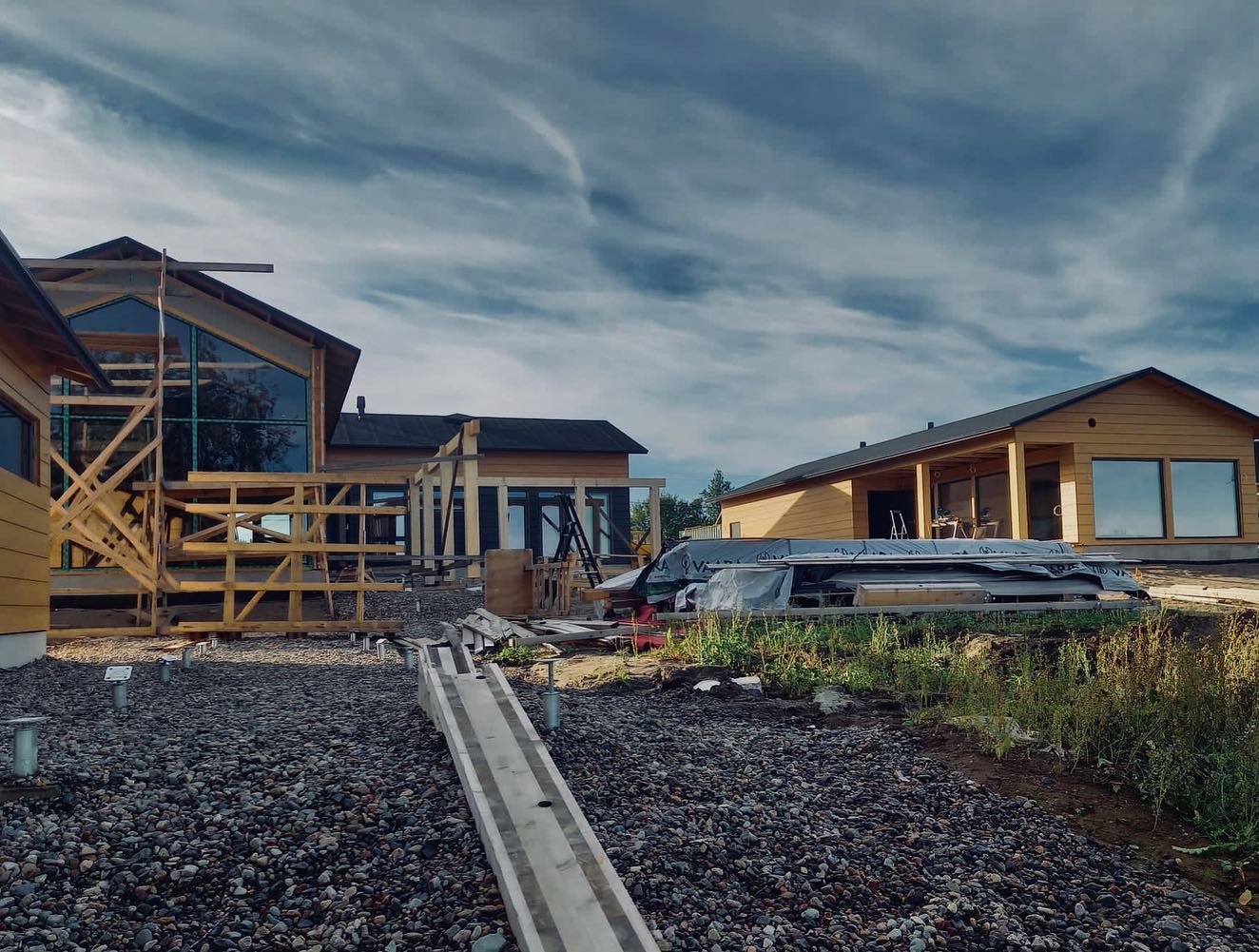 Rakenteilla olevia puutaloja kivipohjalla pilvisen taivaan alla, valaistus on luonnollinen ja valoisa.